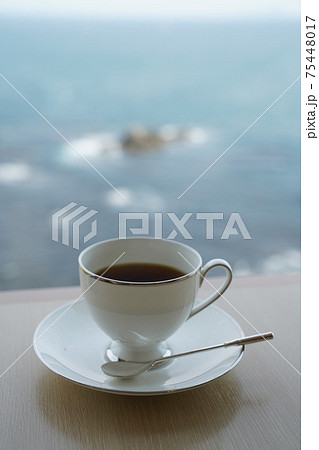 明るい窓辺で海を眺めながらコーヒー 75448017