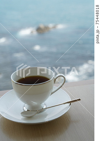 明るい窓辺で海を眺めながらコーヒー 75448018