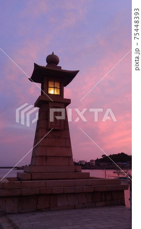 夕焼けに輝く広島県福山市・鞆の浦のシンボル「常夜灯（燈籠塔）」タテ 75448393