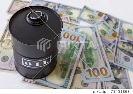 Barrel of oil on a background, american dollars background. Word on barrel is Oil. Falling trend of barrel price decrease of earning and global economics . Selective focus. 75451868