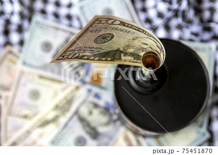 Barrel of oil on a background, american dollars and arabian background. Falling trend of barrel price decrease of earning and global economics . Selective focus. Barrel of oil on a background, american dollars and arabian background. Falling trend of barrel price decrease of earning and global economics . Selective focus. 75451870