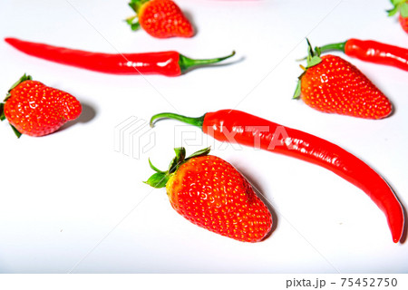 red chili peppers and ripe strawberries on a white background red chili peppers and ripe strawberries on a white background 75452750