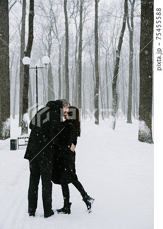A man and a woman on the background of a snow-covered forest in a snowfall 75455588