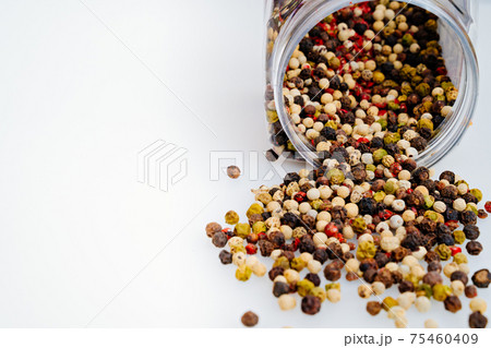 a mixture of peppers is scattered from a jar on a white background. a mixture of peppers is scattered from a jar on a white background. 75460409