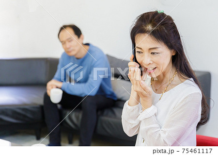 電話をする女性と会話が気になる男性の写真素材