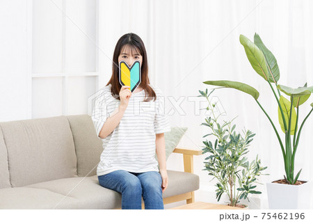 ソファに座って初心者マークを手に持つ若い女性 ソファに座って初心者マークを手に持つ若い女性 75462196