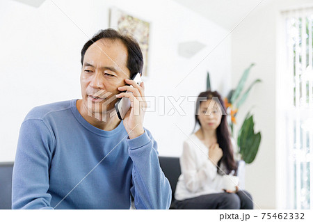電話をする男性と会話が気になる女性の写真素材