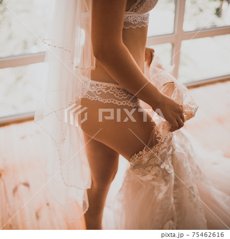 European skinny bride in lingerie puts on a wedding dress 75462616