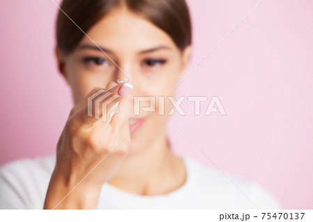 Young woman holding contact lens on finger. Young woman holding contact lens on finger. 75470137