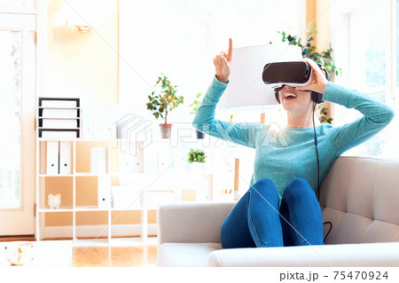 Happy young woman using a VR headset 75470924