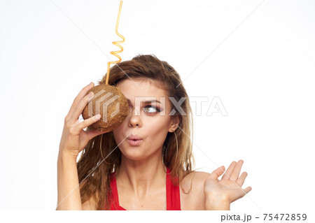 Woman with coconut in hands cocktail enjoying bright makeup Red t-shirt light background 75472859