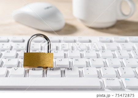 Metal padlock on a white computer keyboard. Closed lock on a desktop keypad. 75472875