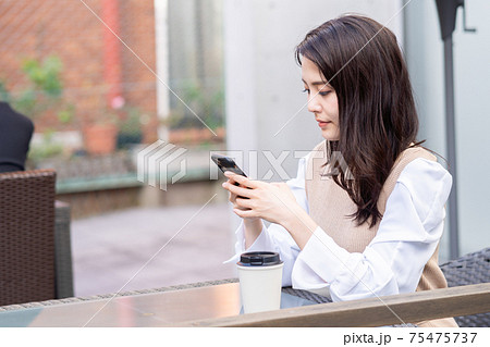 カフェでスマホを操作する若い女性 カフェでスマホを操作する若い女性 75475737