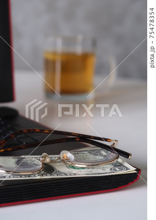 Glasses and dollar bills on the laptop keyboard against the background of a glass of tea with lemon, remote work, work on the Internet, freelancer Glasses and dollar bills on the laptop keyboard against the background of a glass of tea with lemon, remote work, work on the Internet, freelancer 75478354