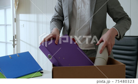 Businessman put things and documents on his desk into the paper box. Businessman put things and documents on his desk into the paper box. 75480323