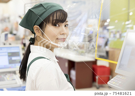 感染対策をしたスーパーのレジで仕事をする女性従業員  シート越し 感染対策をしたスーパーのレジで仕事をする女性従業員  シート越し 75481621
