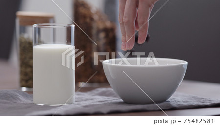 serving chocolate granola pour in white bowl on walnut table 75482581