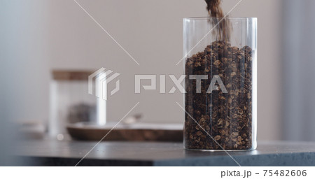 man chocolate granola pour into glass beaker jar on concrete countertop 75482606
