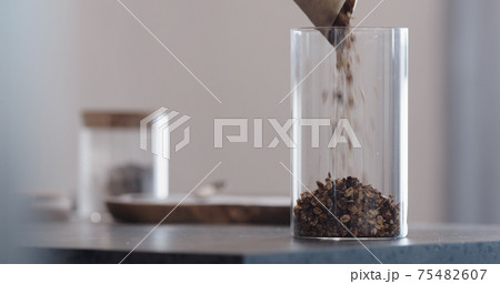 man chocolate granola pour into glass beaker jar on concrete countertop 75482607
