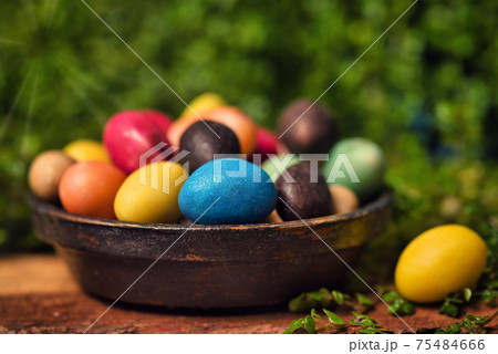 Chocolate Easter eggs with egg candies on a wooden table in the yard 75484666