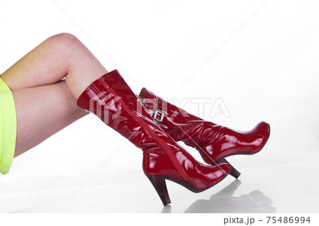 Beautiful legs in beautiful red patent leather boots. Isolated on white background 75486994