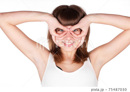 Young woman makes glasses with fingers. The girl looks in impromptu glasses, hand gesture. Isolated 75487030