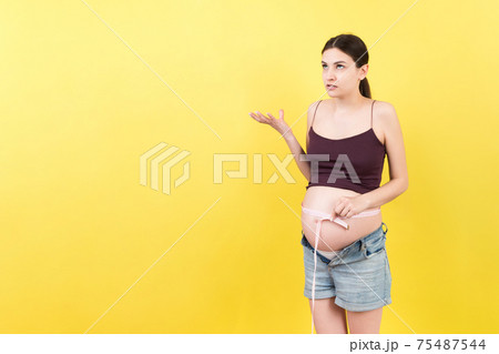 pregnant woman using tape measure to check baby development and the growth of belly. Inch measurement pregnant woman using tape measure to check baby development and the growth of belly. Inch measurement 75487544