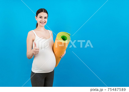 Pregnant Girl Holding Yoga Mat Standing Over Colored Background. Studio Shot, Free Space For Design Pregnant Girl Holding Yoga Mat Standing Over Colored Background. Studio Shot, Free Space For Design 75487589