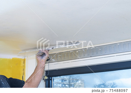 Hand of builder worker spacks ceiling with putty plaster aligning ceiling with spatula Hand of builder worker spacks ceiling with putty plaster aligning ceiling with spatula 75488097