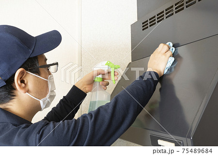 ガスレンジの換気扇カバーの掃除をするハウスクリーニングの男性作業員 75489684