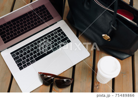 The laptop with the woman's purse and coffee outdoors 75489866