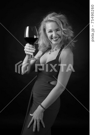 Attractive middle age woman in evening dress with glass of red wine. Attractive middle age woman in evening dress with glass of red wine. 75490260