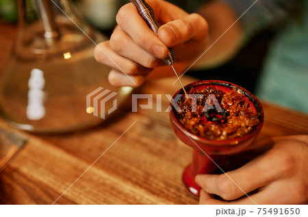 Hookah maker prepares hooka for smoking in bar 75491650