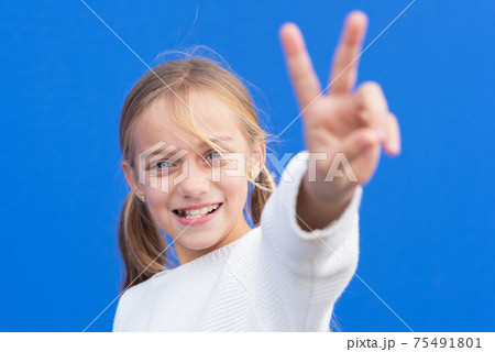 Young beautiful blond girl wearing casual sweater over blue background smiling looking to the camera Young beautiful blond girl wearing casual sweater over blue background smiling looking to the camera 75491801