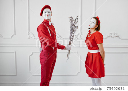 Mime artists in red costumes, scene with bouquet 75492031