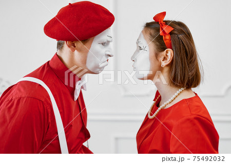 Mime artists in red costumes look at each other 75492032