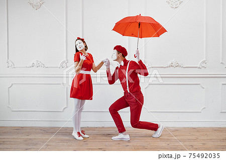 Mime artists in red costumes, scene with umbrella 75492035