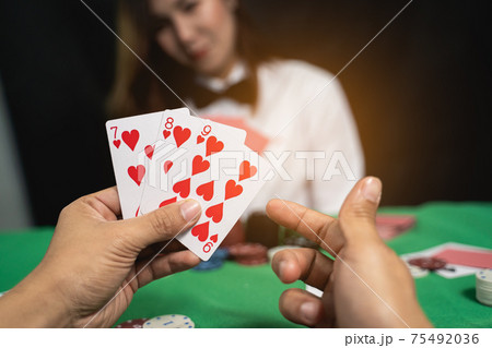 Women dealer or croupier shuffles poker cards in a casino on the background of a table, poker game concept 75492036