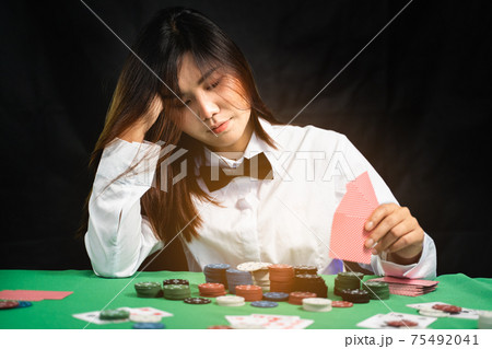 Women dealer or croupier shuffles poker cards in a casino on the background of a table, poker game concept 75492041