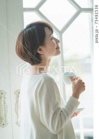 窓辺に佇んでコーヒーを飲むショートヘアーのミドル主婦 窓辺に佇んでコーヒーを飲むショートヘアーのミドル主婦 75492536