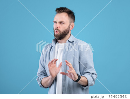 Disgusted young guy refusing something, gesturing NO or STOP over blue studio background Disgusted young guy refusing something, gesturing NO or STOP over blue studio background 75492548