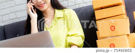 Young asian woman is entrepreneur talking with customer and using laptop computer while order. 75492603