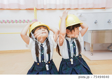 ヘルメットを被り避難する子供 75494640