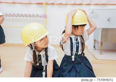 ヘルメットを被り避難する子供 75494641