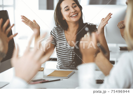 Group of business people discussing questions at meeting. Headshot of casual dressed businesswoman happy smiling to her colleague at office negotiation. Teamwork and cooperation in corporate 75496944