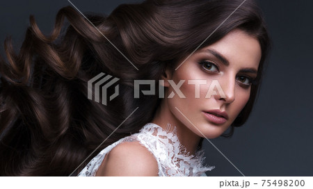 Beautiful brown-haired girl with a perfectly curls hair, and classic make-up. Beauty face and hair. 75498200