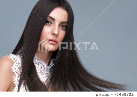 Beautiful brown-haired girl with a perfectly smooth hair, and classic make-up. Beauty face and hair. 75498202