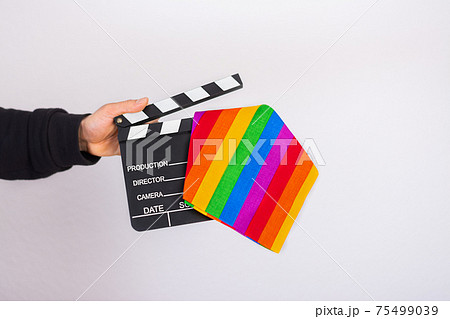 A man hand holding a Lgbt rainbow flag and movie clapper board 75499039
