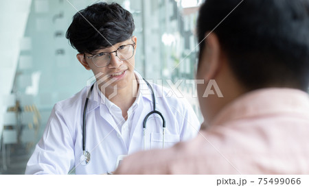 Young Asian man in a white robe talks to a man, Doctors diagnose diseases and give advice or treatment solutions to patients in the hospital examination room, Explaining medical examination results. 75499066