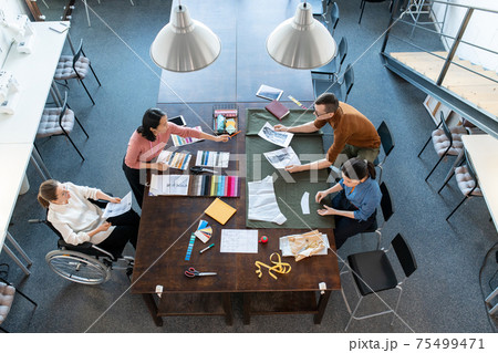 Group of young fashion designers discussing sketches and samples for new seasonal collection 75499471